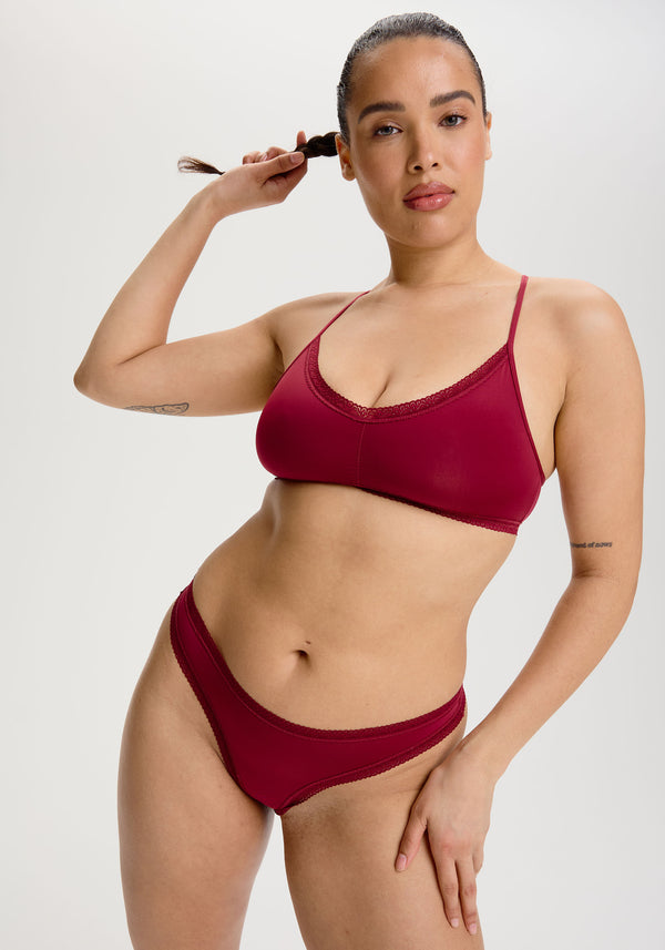 model is wearing an S+ bralette - red the micro lace trim thong